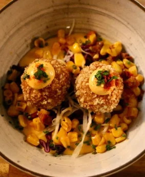 Deux croquetas maison dorées posées sur du maïs